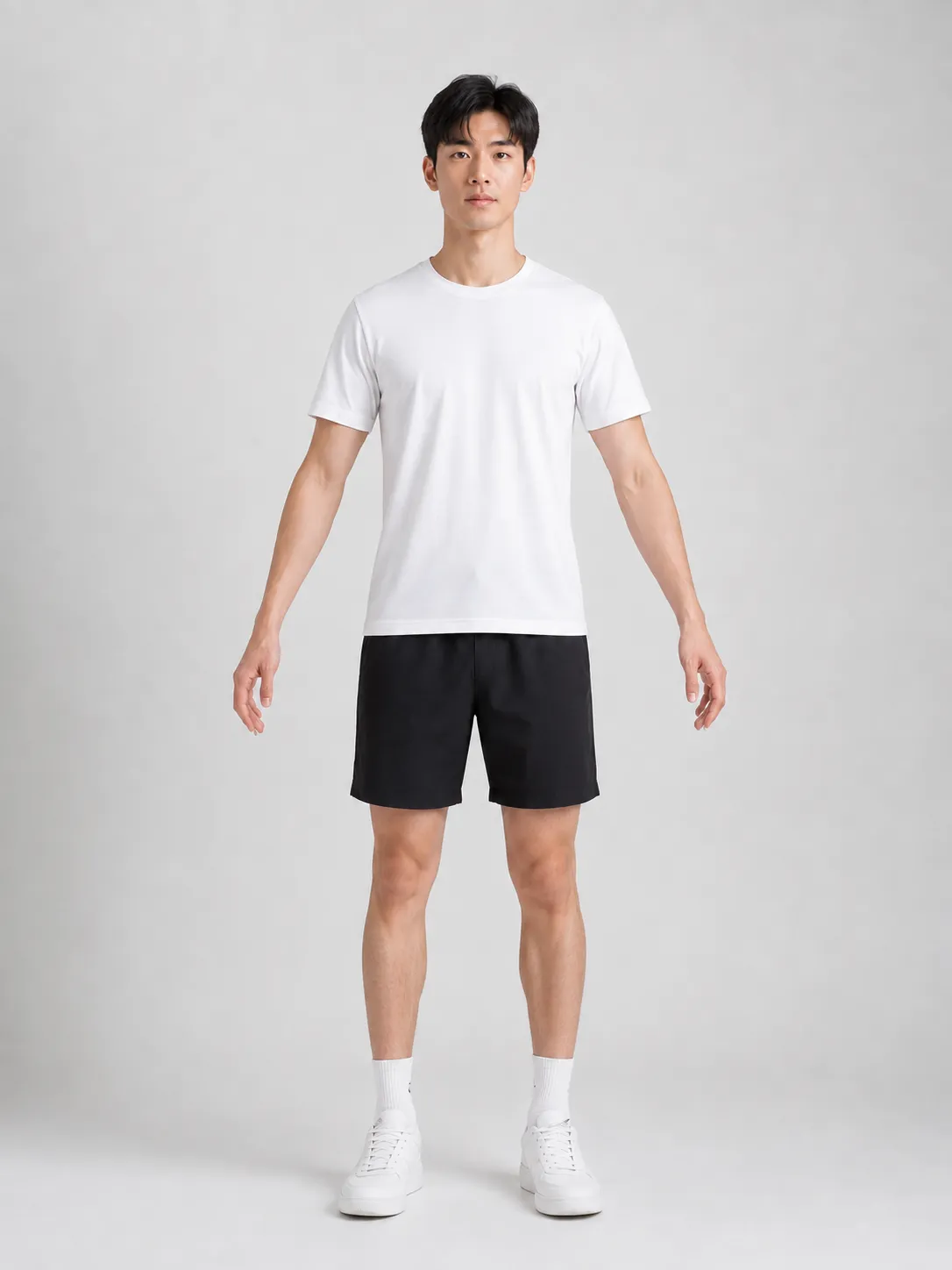A full-length photograph of a person standing in an A-pose against a plain backdrop, in a plain t-shirt and shorts.